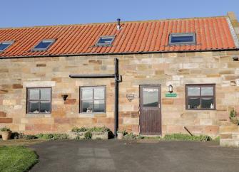 Stone built Whitby holiday home with terracotta tiles and Velux windows on the roof overlook a lawn and parking space