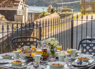 A patio table laid for tea in a Fowey holiday cottage with views to the waterside.