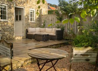 A stone built holiday cottage in Ampleforth with a deck and courtyard containing outdoor seating option.
