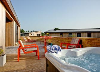 holiday lodge deck with a hot-tub, table and chairs