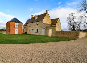 Exterior of a large stone-built, 3-storey Oxfordshire farmhouse and garden.