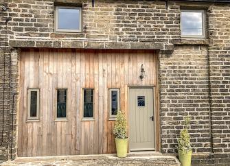Exterior of a stone-built, Pennine barn conversion with wood-panelled walls and