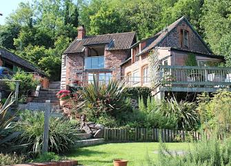 A restored coach house with a large deck surrounded by a flower and shrub filled garden on Exmoor.