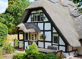 A half-timbered and thatched Tudor Cotswold cottage and garden.