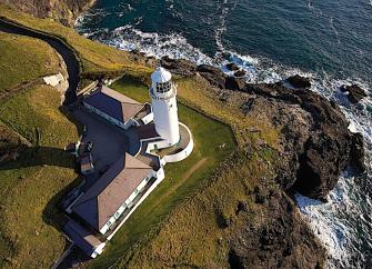Aerial view of a Cornish Lighthouse complex overlooking the sea.