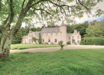A Highland Country House surrounded by wooded parkland.