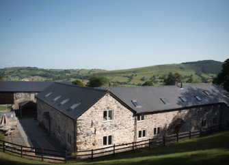 Exterior view of a stonebuilt, L-shaped barn conversion in the Shropshire Countryside.