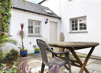 Whitewashed exterior of a Cornish cottage overlooking a courtyard.