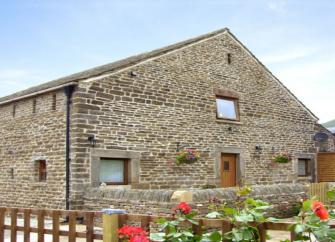 Exterior of a 2-storey, stone-built barn conversion overlooking a low-walled garden