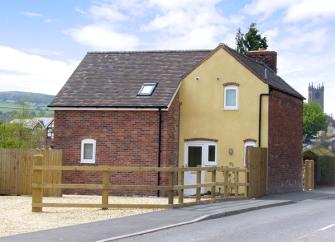 A 2-storey holiday cottage has generous off-road parking outside the front door and a garden behind.