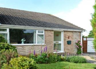 A holiday bungalow in oakerthorpe over looking a lawn with wel-kept flower beds and shrubs.