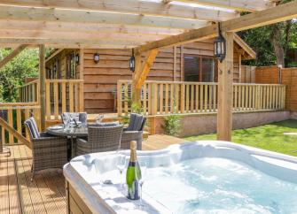 A wooden holiday lodge in Washford overlooks a patio with a hot tub. on a terrace/