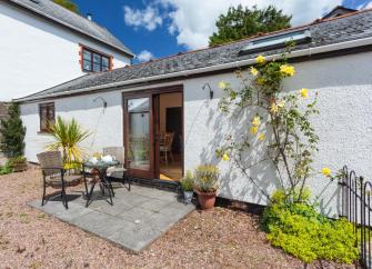 A single storey cottage with dining table and chair in its courtyard garden
