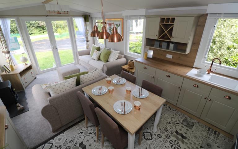 Interior of a modern static caravan showing the open plan lounge, dining and kitchen areas.