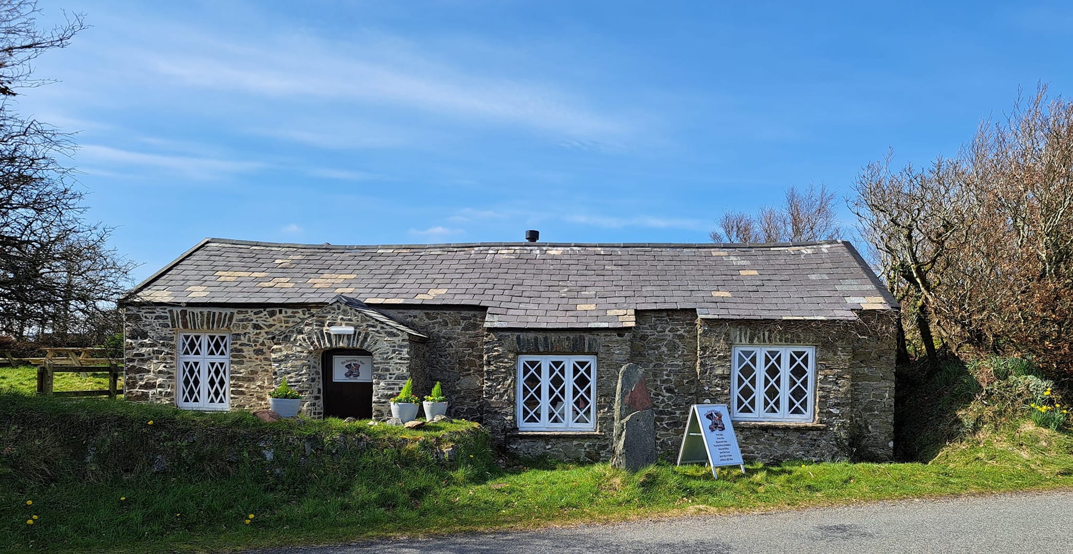Ramblers Rest Tearooms is a single story, stone-built tearooms with latticework iron windows surrounded by shrubs and fields near Lynmouth.