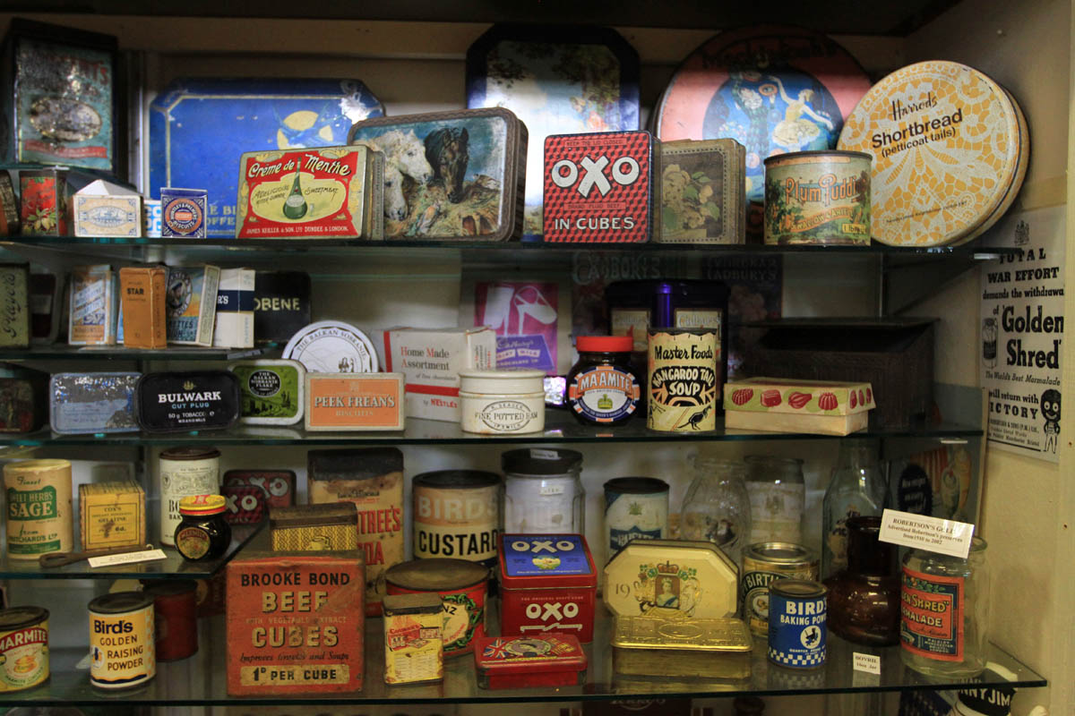 shelves displaying old metal tin cans of branded food such as Oxo and Brooke Bond Beef Cubes.