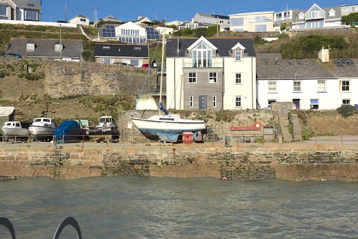 A row of Portreath townhouses overlook a quayside at high tide.