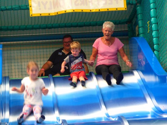 A grandmother and two young children at the top of a giant slide.