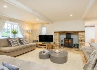 The spacious lounge at Culls Cottage with soft furnishings, woodburner, TV and other home comforts.