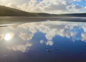 A mirror reflection of blue sky and clouds in the wet sand on Woolacombebeach