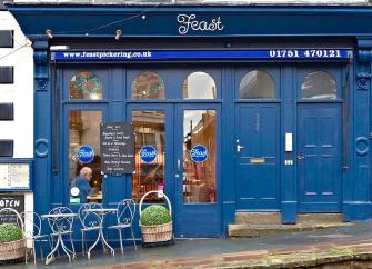 Feast cafe shop front in Pickering with large windows through which tables and chair can be seen