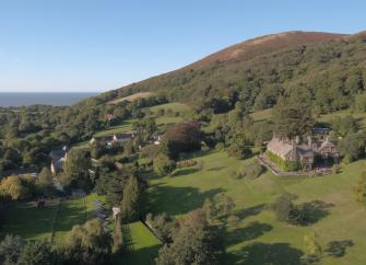 A cluster of village cottage roofs nestle beneath a moorland hill.