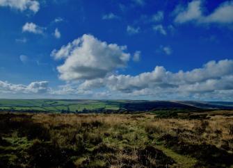 Rows of cumulous clouds float above Exmoor across open moorland.