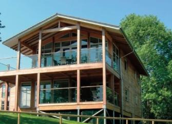A large holiday lodge in a rural setting with an oak framework and large glass windows=
