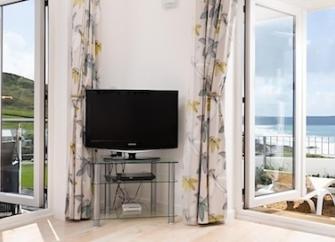 A lounge with dual aspect floor-to-ceiling French windows offering Woolacombe Beach views.