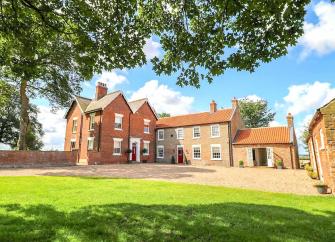 Exterior of a large, brick-built manor house overlooking a spacious courtyard.