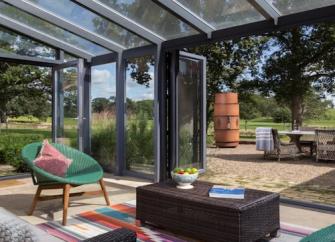 A contemporary conservatory with bi-fold French windows opening on to a garden patio.