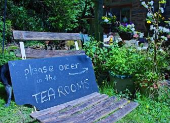 A blackboard sign  perched on a wooden chair welcoming customers to an Exmoor Tearoom