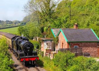 A steam engines trundles past a line-side holiday cottage on the West Somerset railway