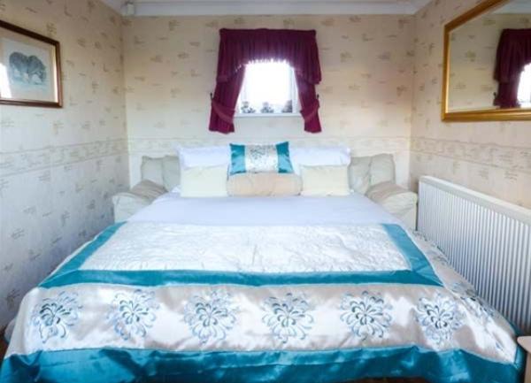 Double bedroom with bed and wide, wall-mounted mirror.