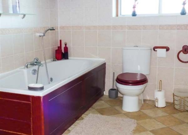 Bathroom with a bath having a hand shower attachment and WC.