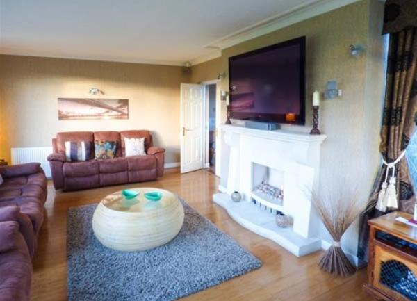 Lounge with leather sofas and armchairs, fireplace and large widescreen TV above it.