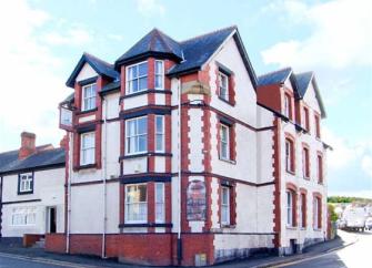 Exterior of a large 3-Victorian Inn on a street corner, now converted into a big holiday cottage.