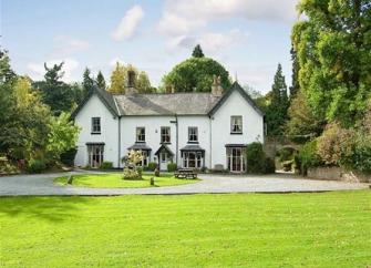 Large rural Shropshire manor house with two end gables overlooks a large, tree-lined lawn.