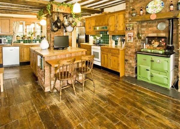 Spacious oak beamed kitchen with a wooden floor. Appliances include an Aga stove, oven dishwasher and a breakfast bar and stools.