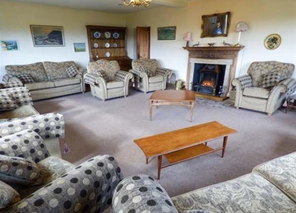 A large lounge with sofas or armchairs on all sides, plus wood burner and coffee table.