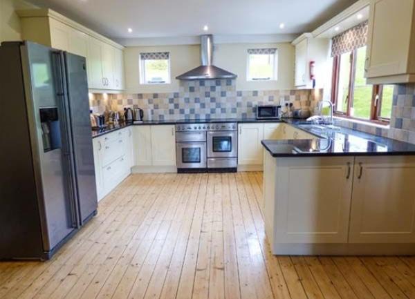 A fitted open-plan kitchen with a full height fridge and freezer and twin ovens.