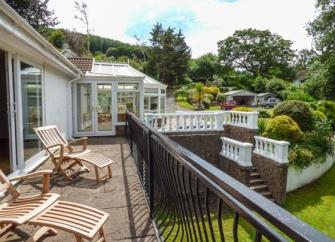 A bungalow with a sun room and terrace overlooks a sunken garden.