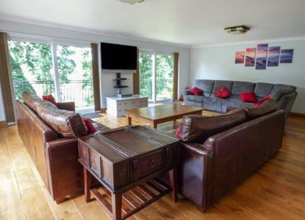 A large lounge with leather sofas gathered around a coffee table and wall-mounted TV.