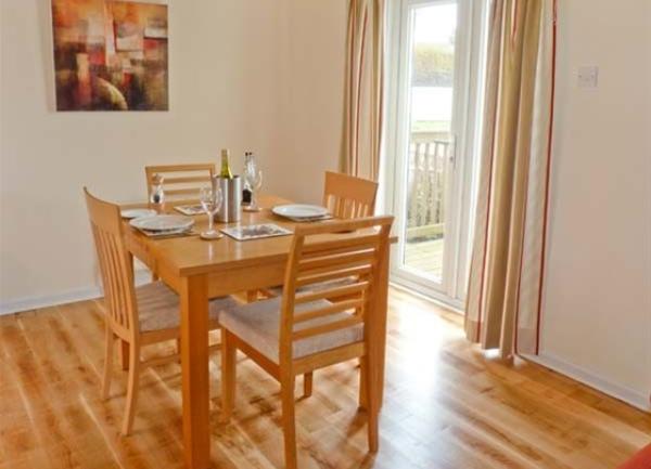 A wood-floored dining room with a polished pine table and four chairs.