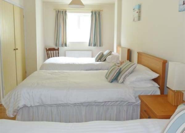 A triple bedroom with three single beds, bedside tables and a built-in wardrobe.