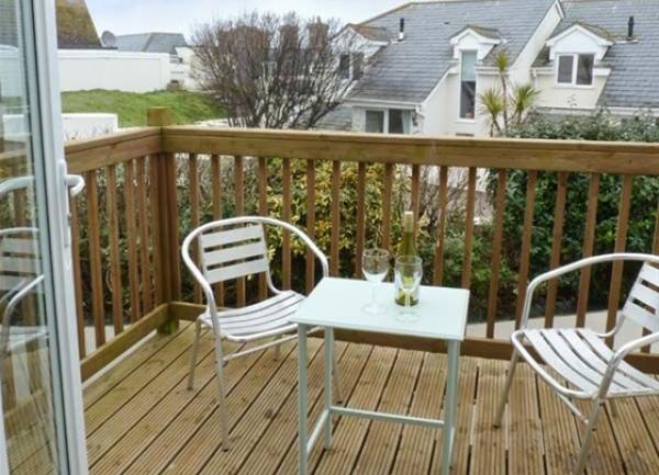 1st-floor wooden deck with a drinks table and two chairs.