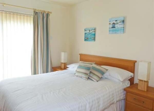 Double bedroom with floor-to-ceiling curtained windows and twin bedside cabinets with table lamps.