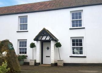 A double-fronted, white rendered Ilfracombe cottage with traditional sash windows