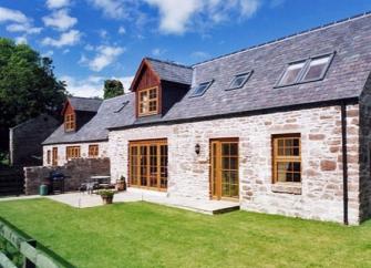 Exterior of a slate-roofed barn conversion with patio and lawned garden.