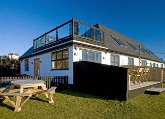 A contemporary house with a large 1st-floor terrace and ground-floor deck.